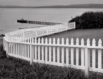 Fence and Pier, Port Townsend, Washington. Black and white photograph